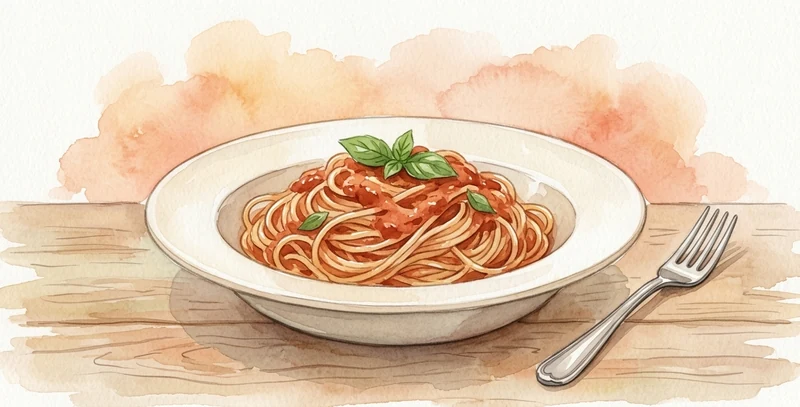 Un plato hondo de pasta con tomate y un tenedor al lado, sobre una mesa de madera.